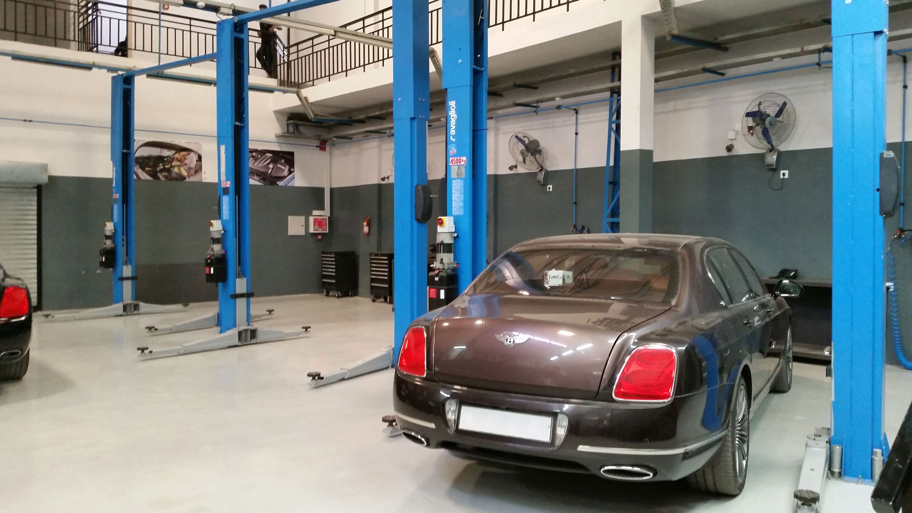 Brown Bentley parked between the columns of a Ravaglioli two-post lift
