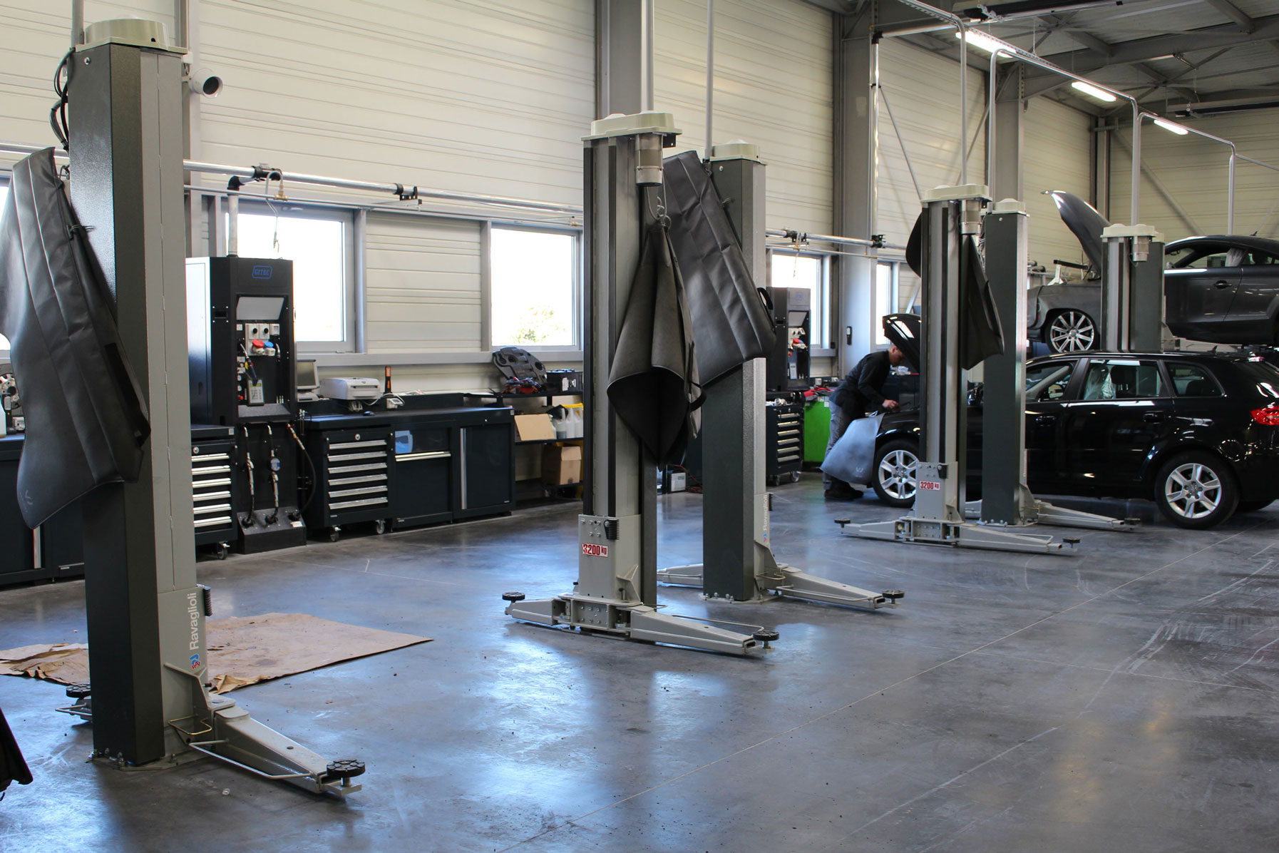 Installation of grey Ravaglioli 2-post lifts in the workshop of a French car dealer