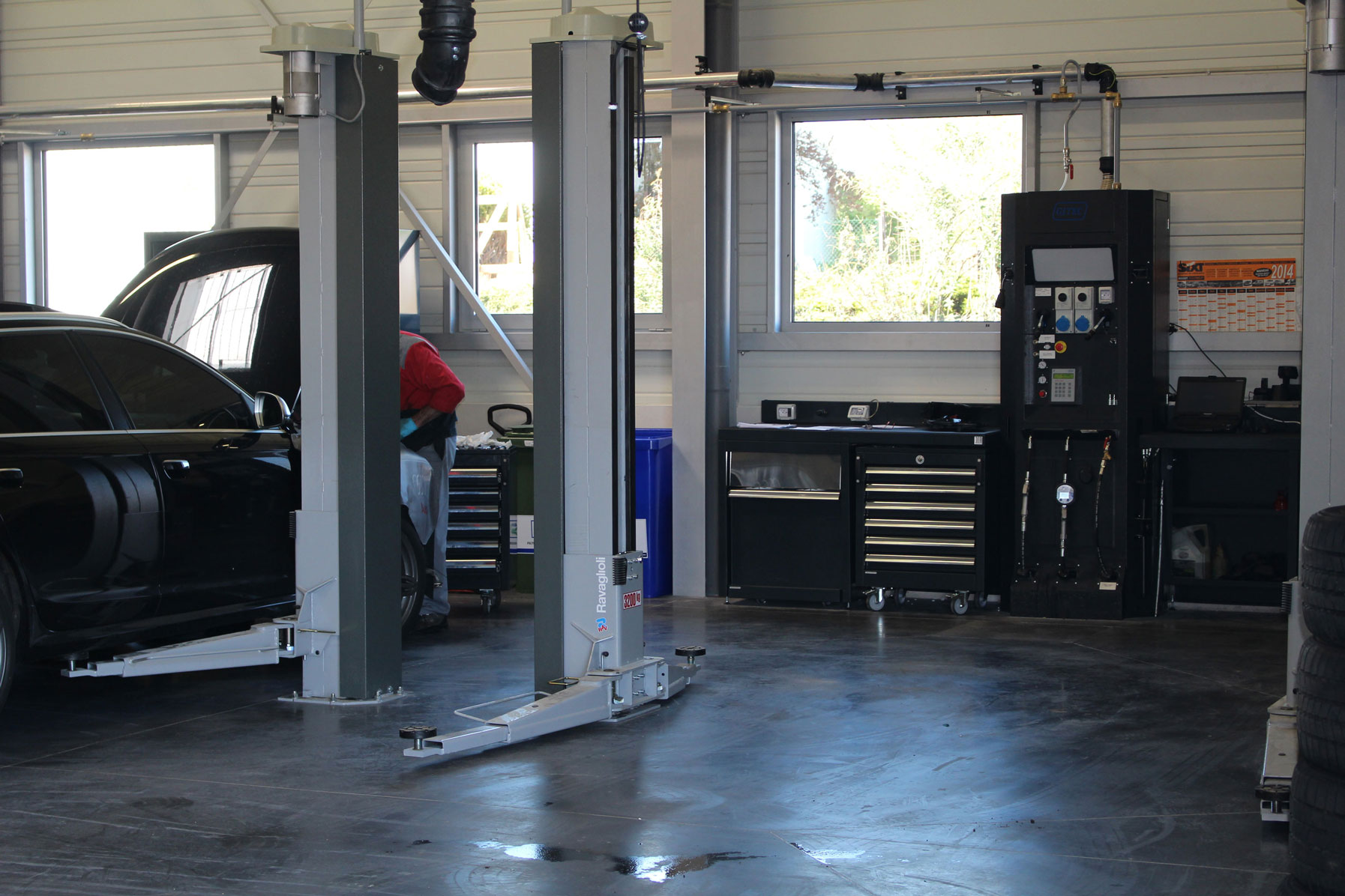 Ravaglioli grey 3.2 tons lift installed in a workshop fitted with mechanics' equipment