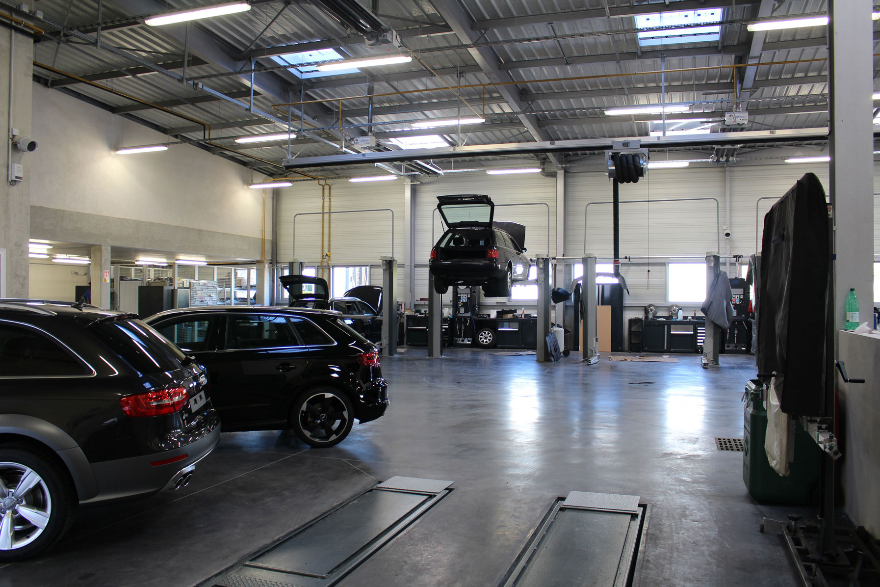 Vehicles placed in an AUDI dealer with some cars undergoing work on 2-post lifts