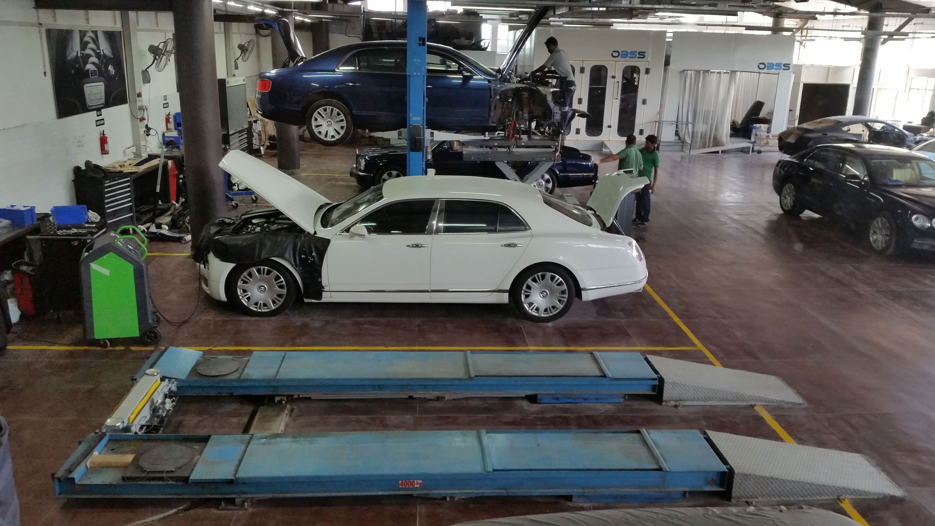 Group of mechanics repair cars inside a dealership equipped with Ravaglioli equipment