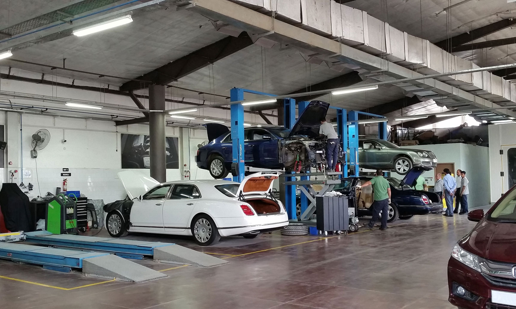 Mechanics repair four Bentley cars in an Indian workshop