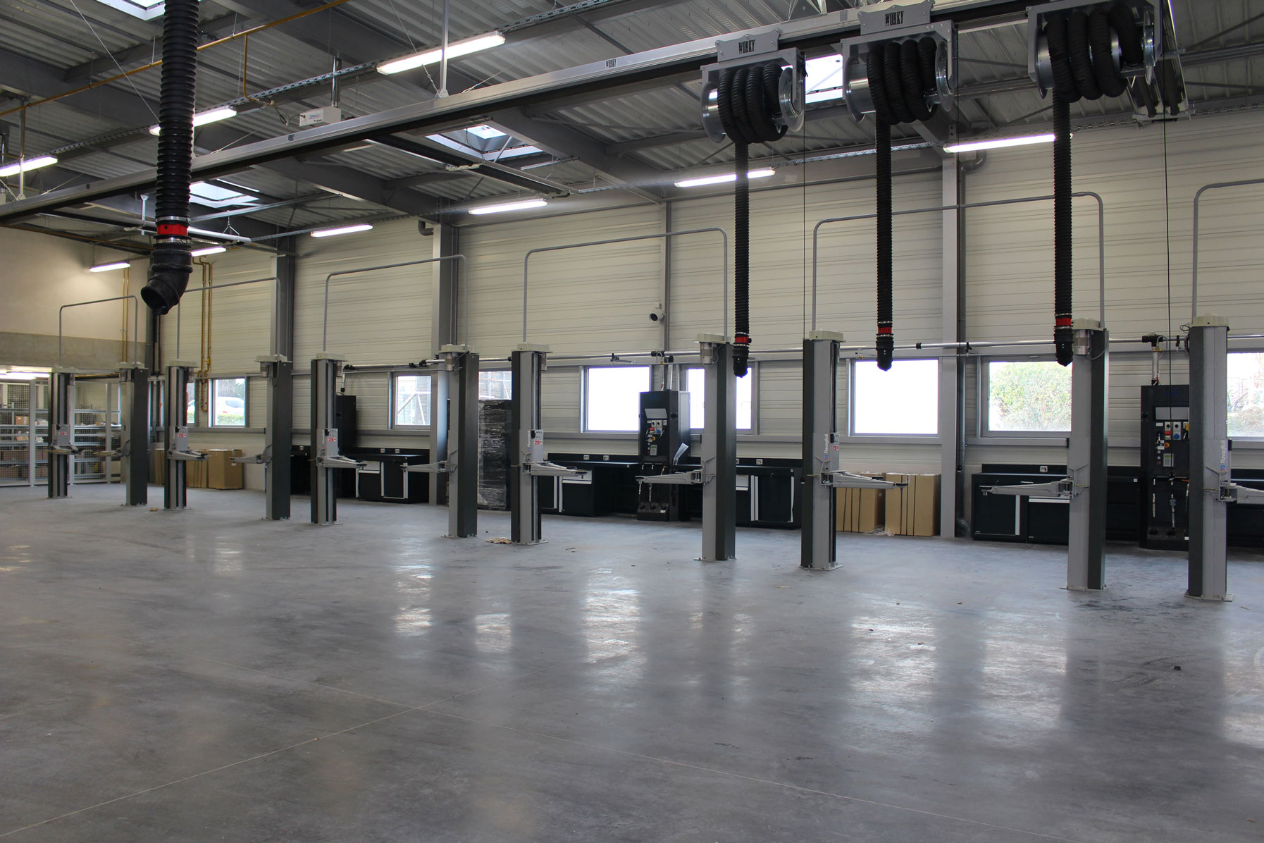 Workshop equipped with numerous grey two-post lifts set up in a row