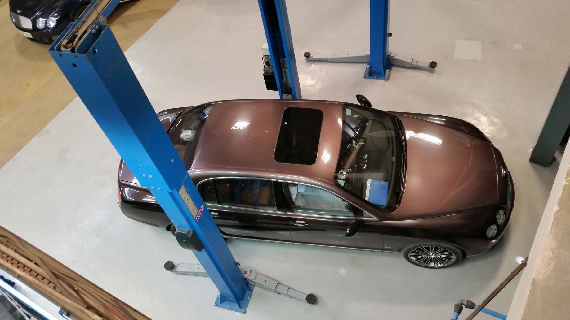 Top view of a brown car being serviced in a workshop