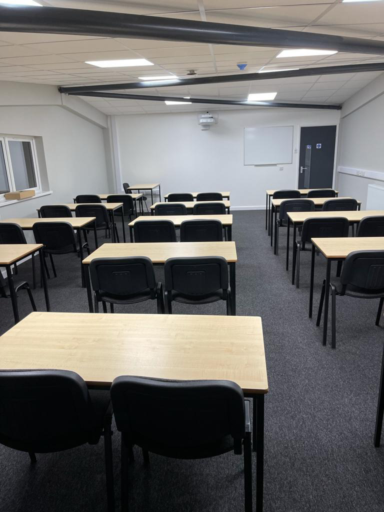 Three rows of desks and chairs positioned in a college classroom with white walls
