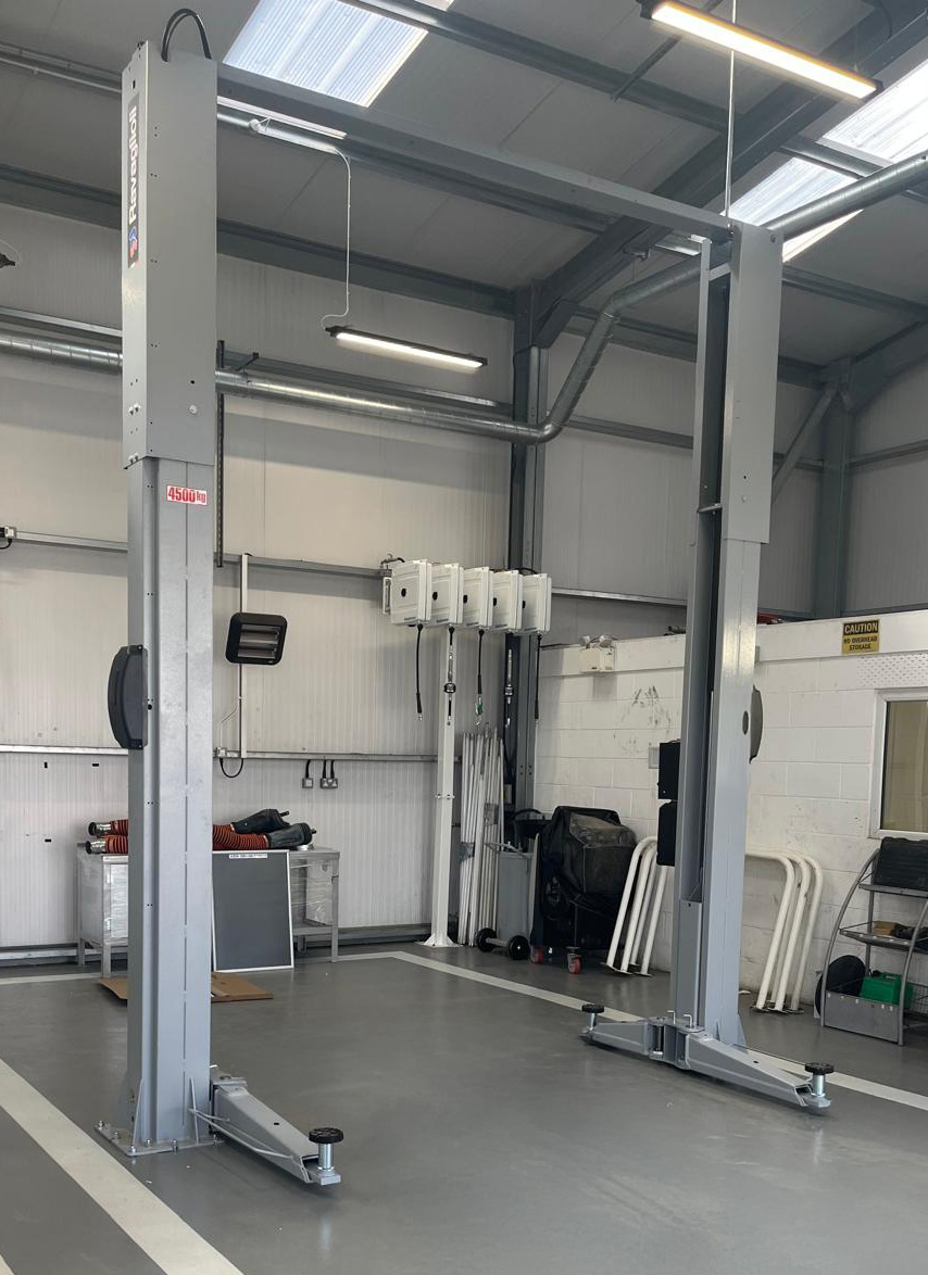 Two-post light-gray car lift installed in a workshop