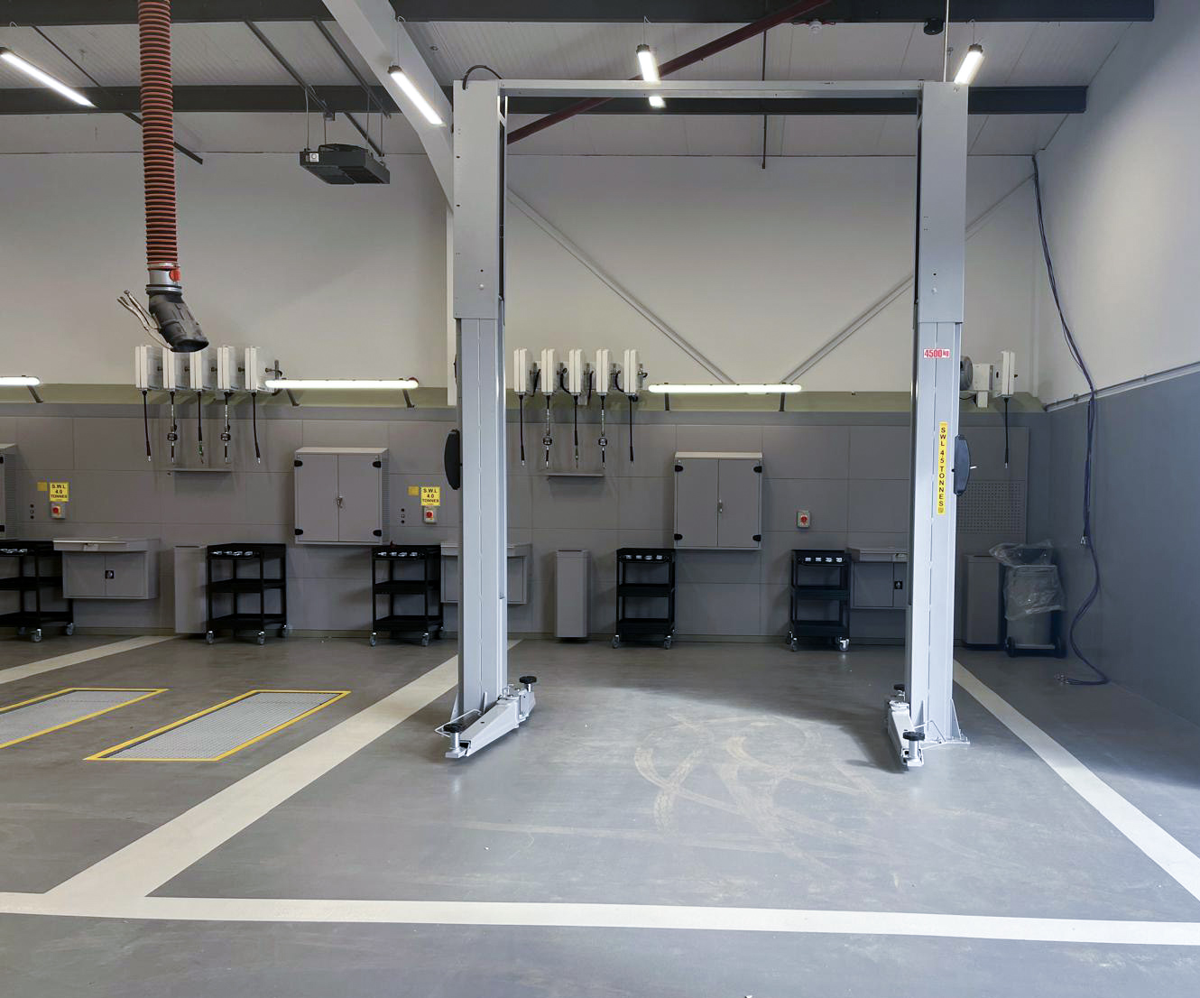 Frontal shot of a workshop to which the right side has installed a scissor lift and the left side a grey 2-post lift