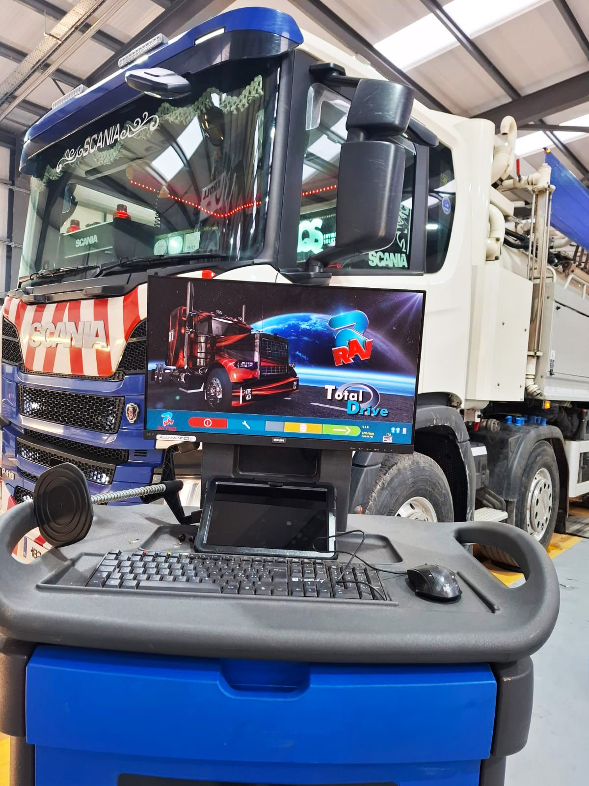 Ravaglioli computer monitor with keyboard positioned in front of a blue and white Scania truck